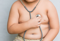 Übergewichtiges Kind das sich mit einem Stethoskop selbst abhört